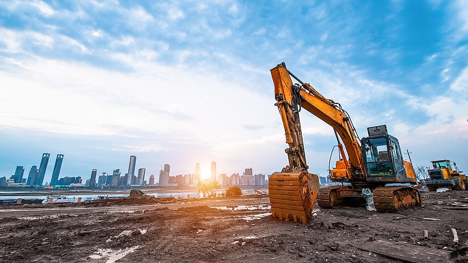 Excavator in a construction site with the city in background
